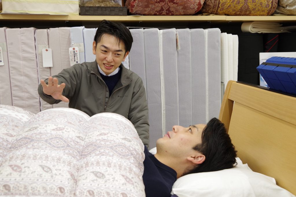 羽毛ふとん寝心地体感フェアで掛け心地を試す様子